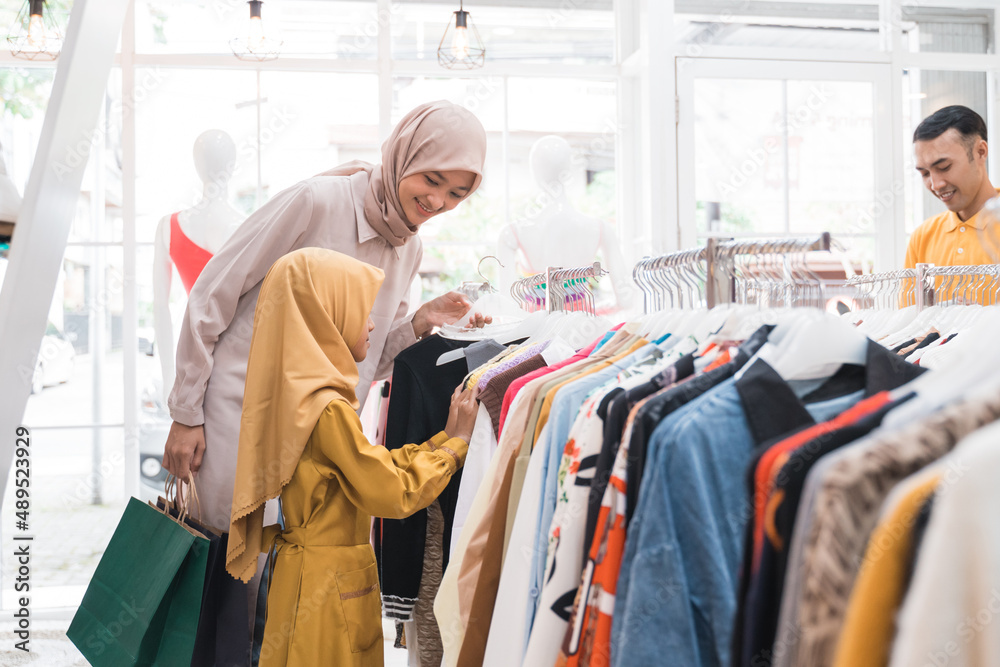 muslim mother choosing shirt with daughter during shopping at fashion shop muslim mother choosing shirt with daughter during shopping at fashion shop