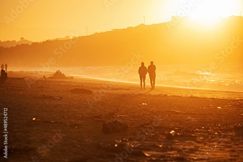 Relaxing young couple silhouette. Man and woman walking by a pathway on a beach.