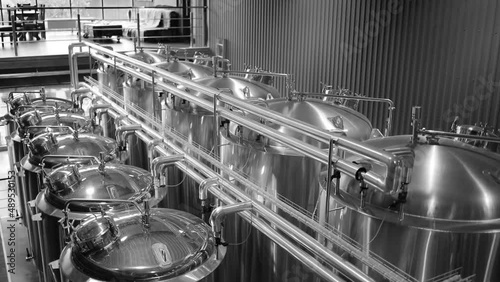 Craft beer production line in private microbrewery. Modern beer plant with brewering kettles, tubes and tanks made of stainless steel photo