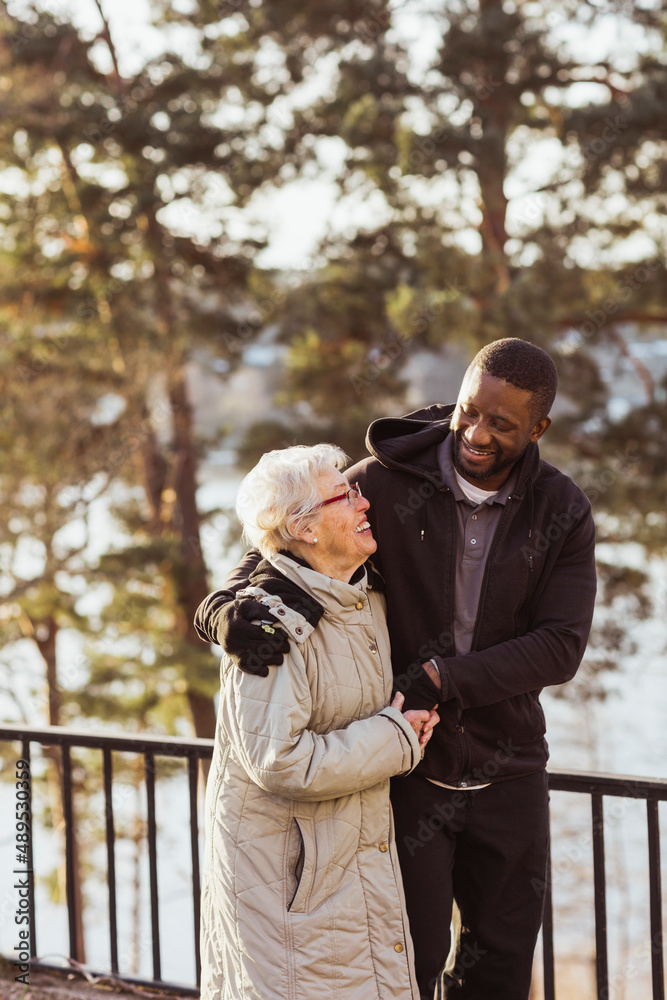 Smiling male nurse walking with senior woman in park Smiling male nurse walking with senior woman in park