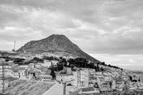 Traditional Spanish whitewashed village with mountain and ruined castle on the sumit. Monochrome black and white