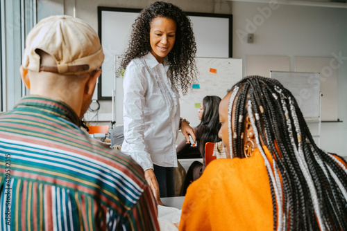 Female professor teaching students in classroom at community college photo