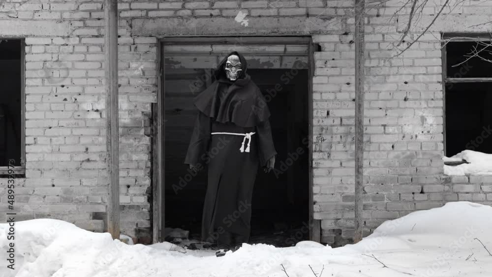 Grim Reaper Standing in the Entrance of Abandoned Brick Building and Looking at Camera in Winter Day. Black and White (Monochrome) Toning Grim Reaper Standing in the Entrance of Abandoned Brick Building and Looking at Camera in Winter Day. Black and White (Monochrome) Toning