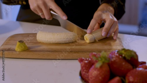 person cutting fruits in the kitchen. Strawberry and banana