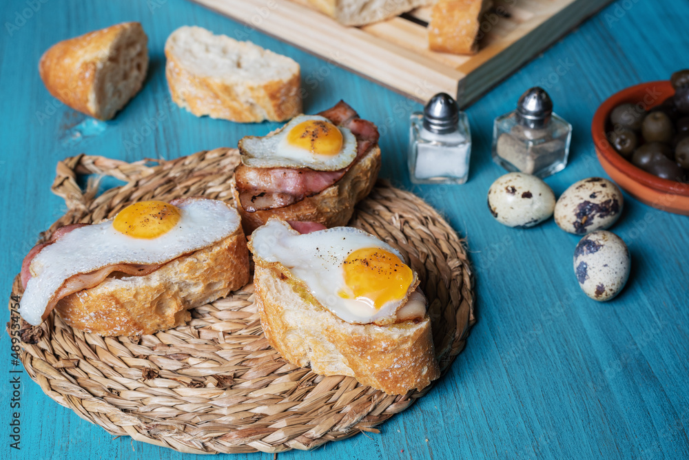 Slice of bread with bacon and grilled quail egg,on a wooden table. Slice of bread with bacon and grilled quail egg,on a wooden table.