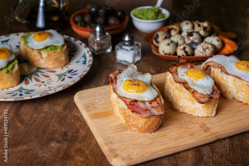 Slice of bread with bacon or avocado and grilled quail egg,on a wooden table.