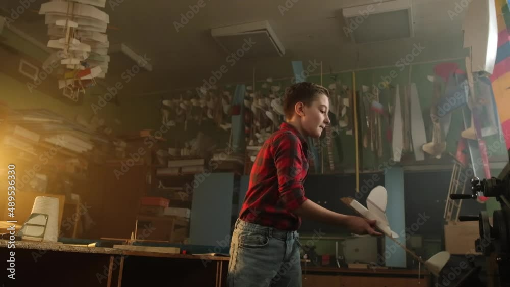 A boy in a red plaid shirt plays with a model airplane A boy in a red plaid shirt plays with a model airplane