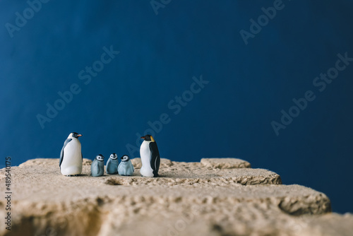 Cute miniature toy penguin colony. Wild animal family.