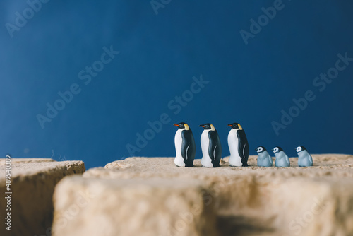 Cute miniature toy penguin colony. Wild animal family.