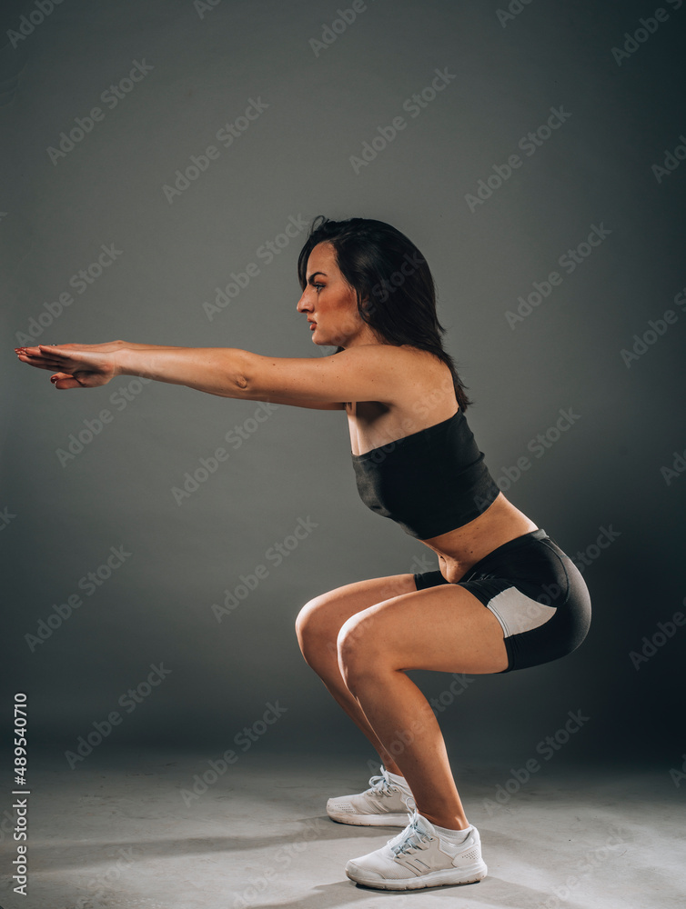 Pretty young woman standing and doing stretching exercises in ballet studio Pretty young woman standing and doing stretching exercises in ballet studio