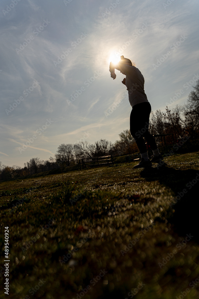 Exercising kickbox alone outside, silhouette. Low angle Exercising kickbox alone outside, silhouette. Low angle