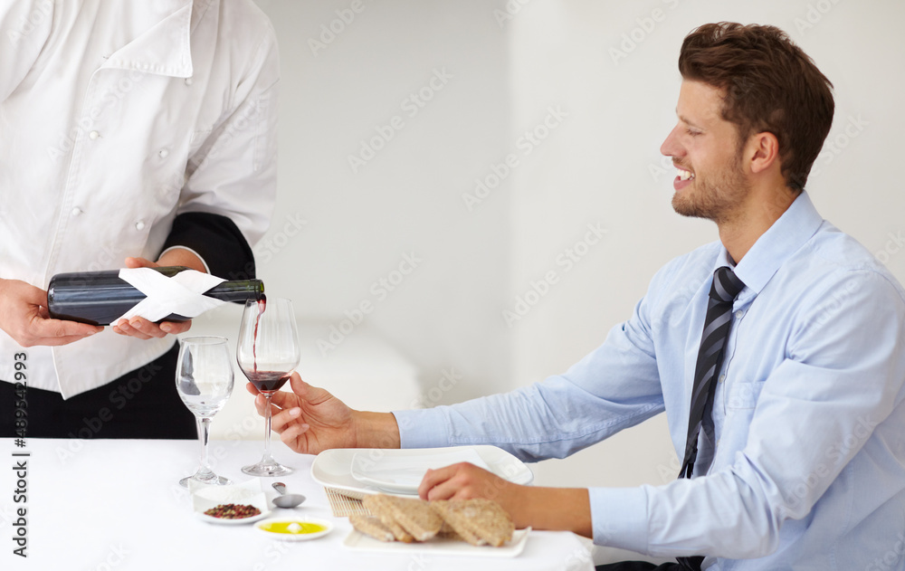 Ready to enjoy a great dining experience. Handsome young man smiling as a sommelier pours wine for him at a restaurant - Fine Dining. Ready to enjoy a great dining experience. Handsome young man smiling as a sommelier pours wine for him at a restaurant - Fine Dining.