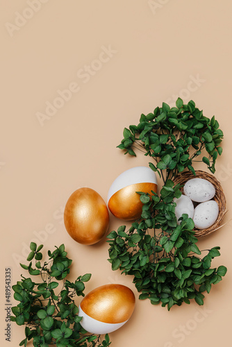 Easter golden eggs with green flowers on beige background. Holiday concept. Happy Easter card.
