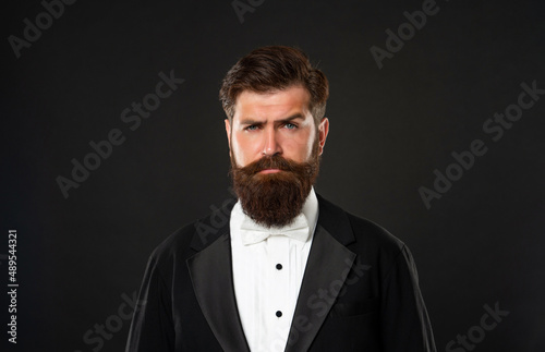 bearded man in tuxedo on black background, fashionist