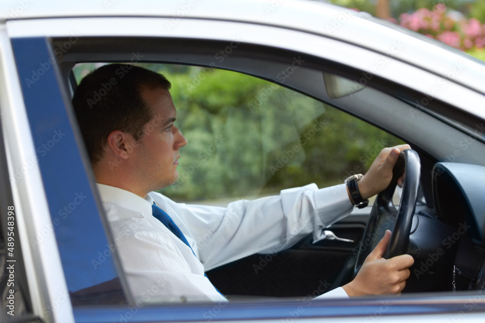 The daily commute. Profile of a businessman driving his car to work. The daily commute. Profile of a businessman driving his car to work.