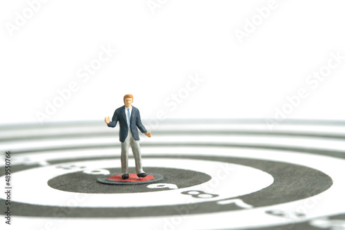 Miniature people toy figure photography. A shrugging businessman standing the center of dartboard. Isolated on white background. Image photo