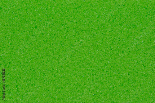 Texture of a foam dishwashing sponge. Background of green sponge for cleaning.