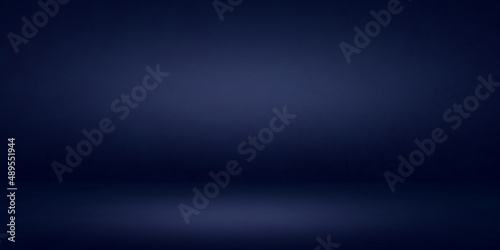 Dark blue cement wall studio background and rough floor soft lighting circular well editing montage products and text present on empty free space backdrop 