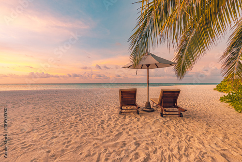 Summer beach landscape. Luxury vacation and holiday concept  summer travel banner. Panoramic landscape of sunset beach  two loungers umbrella  palm leaf  colorful sunset sky for paradise island view