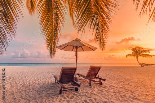 Tranquil beach scene. Exotic tropical beach landscape for background or wallpaper. Design of summer vacation holiday concept. Couple bed, loungers, umbrella with romantic mood. Sunset light, travel 