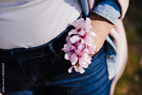 Tablou canvas close up of woman holding pink almond tree flowers in jeans pocket on sunny day