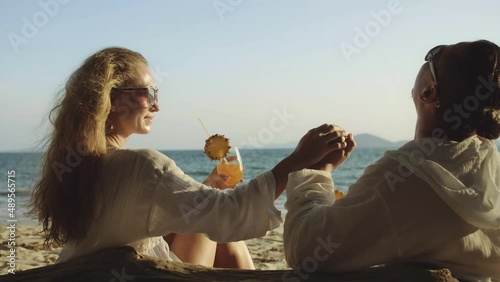 Loving couple in white dress, sunglasses, relax and drinking cocktail Pina Colada. Man kissing hand lady. Concept sea beach resting tropical tourism summer holidays wedding love family vacations