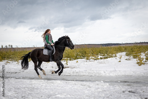 Girl on a black horse. Walk with a horse through the countryside. Russia. Lipetsk 20.02.2022