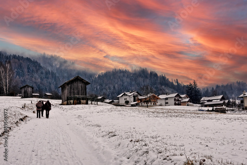  Panorámica nevada en San Martino (Italia) con un cielo rojo invernal y tres personas de espaldas a lo lejos.