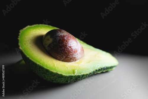 Half an avocado with a pit on a white table. contrast shot soft focus