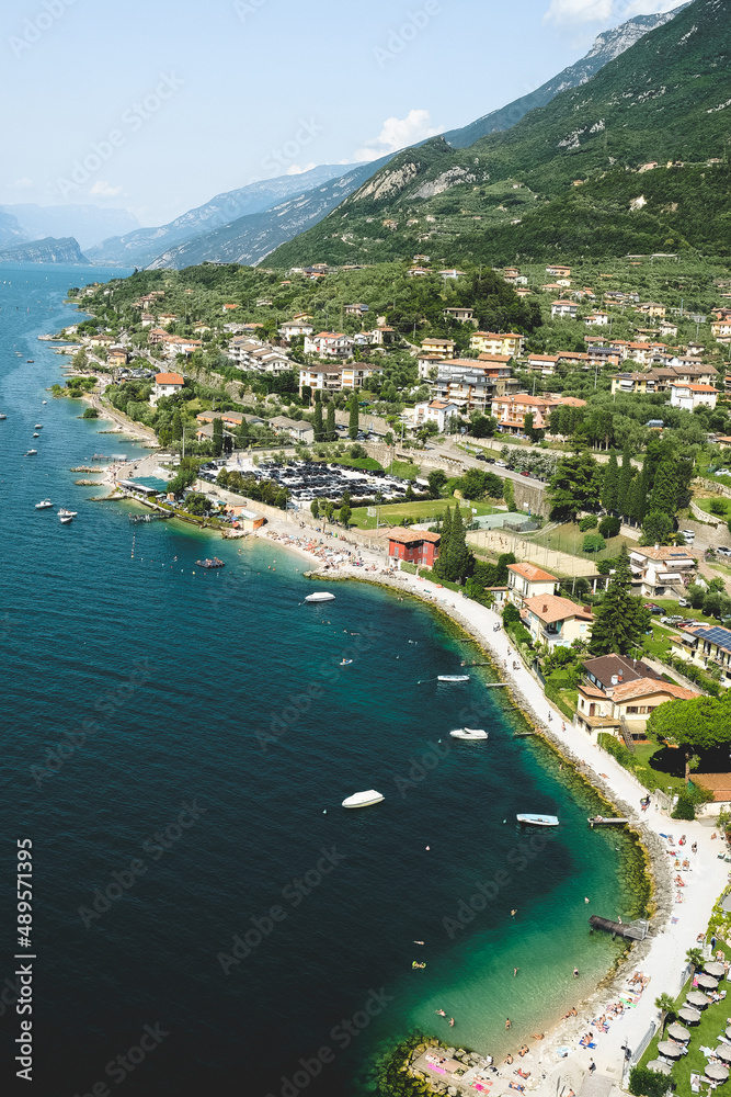 Small mediterranean town Malcesine near lake Garda, Italy, with boats, beach and mountains in the horizon during summer time