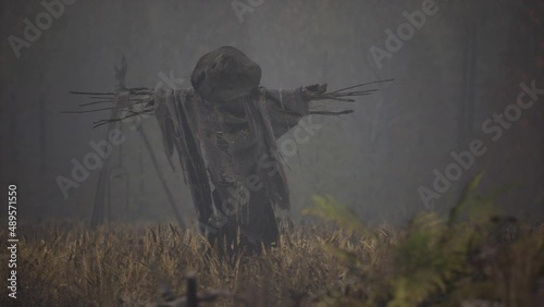 terrible scarecrow in dark cloak and dirty hat stands alone in autumn field