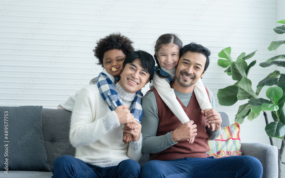 Asian young Lgbtq gay couple enjoy playing with little adopted Caucasian and African kid in living room at home. Happy daughter and son hugging and riding on back of dad. Diverse Lgbt family concept Asian young Lgbtq gay couple enjoy playing with little adopted Caucasian and African kid in living room at home. Happy daughter and son hugging and riding on back of dad. Diverse Lgbt family concept