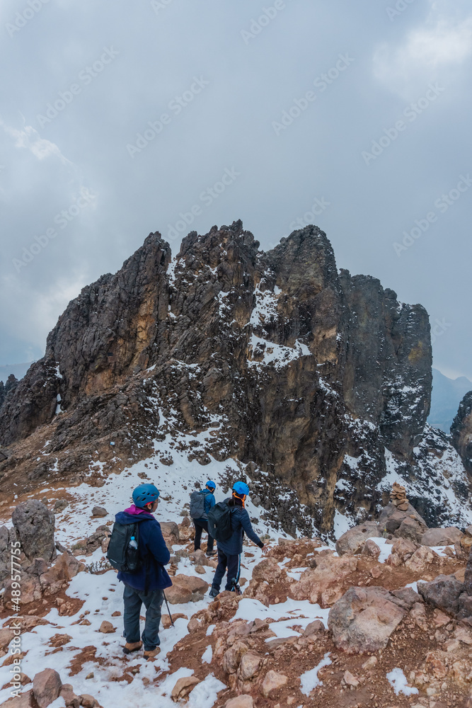 Group of hikers ascending on snow-capped mountain peak