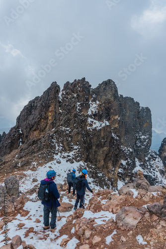 Group of hikers ascending on snow-capped mountain peak