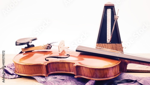 prezioso violino acustico con borsa in seta e metronomo con parete bianca come sfondo photo