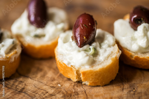 Small piece of bread with tzatziki spread and olive,closeup.