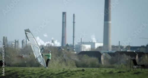 Windskating in the industrial area. Surf sail windskater on a path in front of the industry with chimneys.