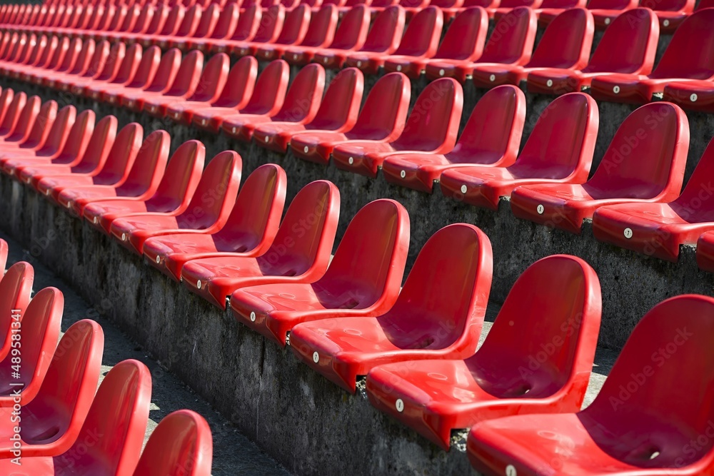 red benches of football - athletic stadium, sun set, place for spectators and athletes