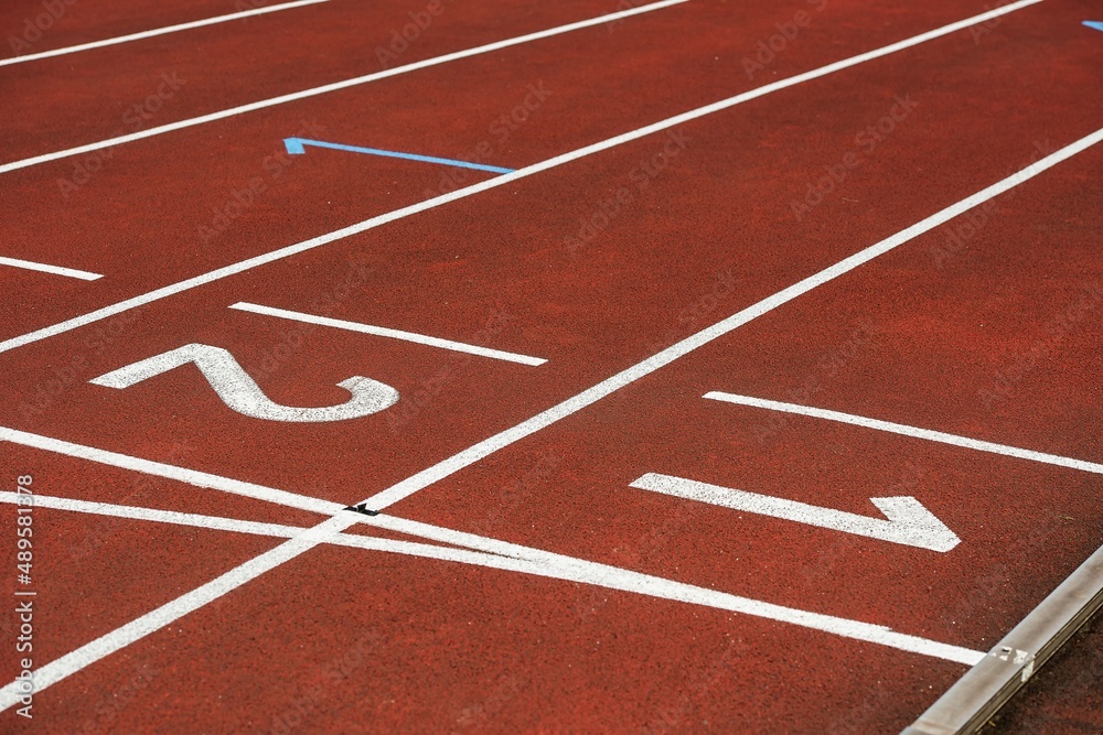 Running tracks. Red tartan on an athletic stadium. White and yellow lines. Sunny sunny day.