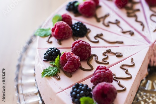 Raspberry creamy cake on a glass tray, laid on a table.