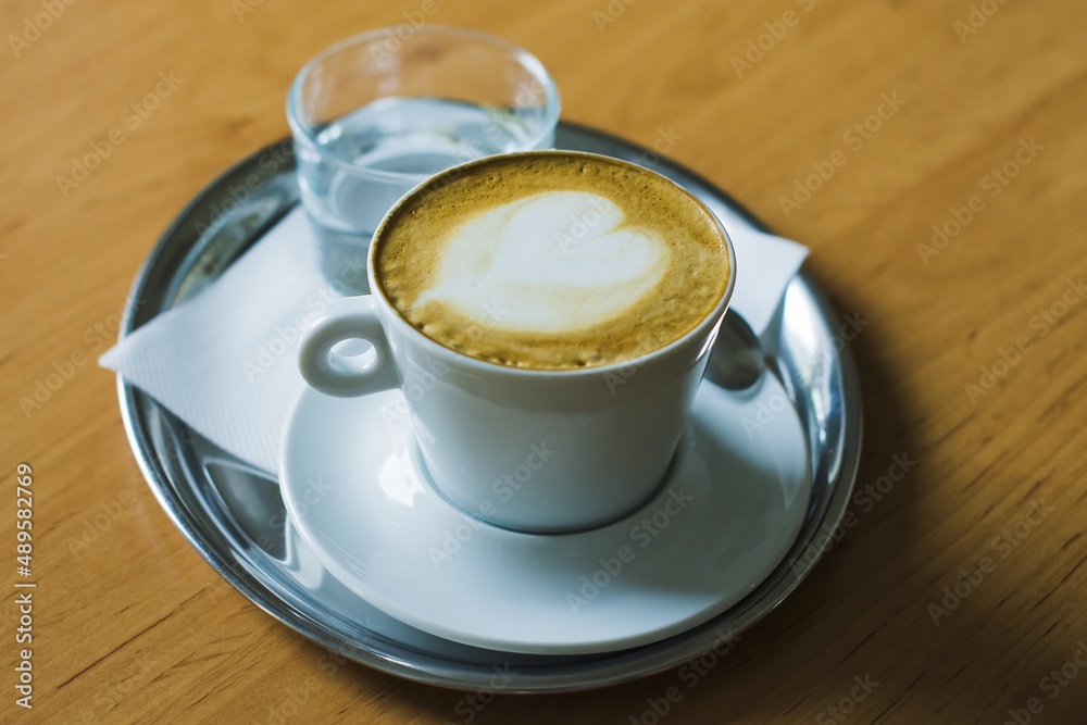 Obraz premium Coffee with water on a stainless steel mat, laid on a wooden table.