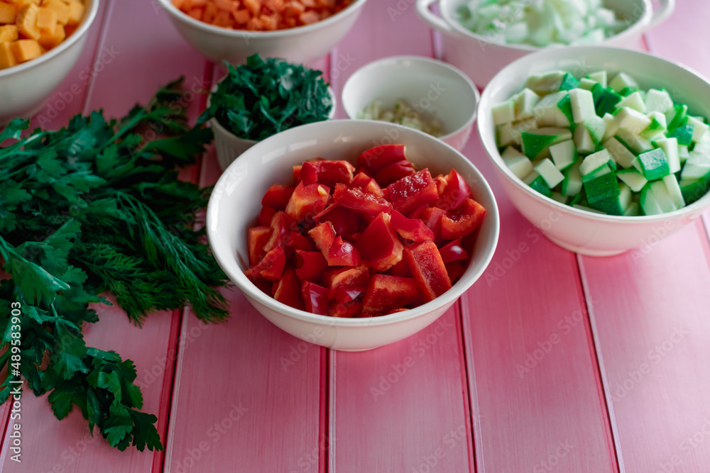 Fresh Bulgarian sweet red pepper diced in a bowl, on a pink wooden background, fresh vegetables for cooking in the kitchen, prepared ingredients Fresh Bulgarian sweet red pepper diced in a bowl, on a pink wooden background, fresh vegetables for cooking in the kitchen, prepared ingredients
