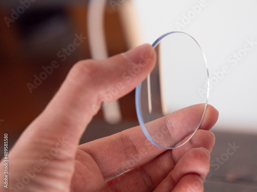One clear lens  hand holds an eyewear round lens for quality control.
