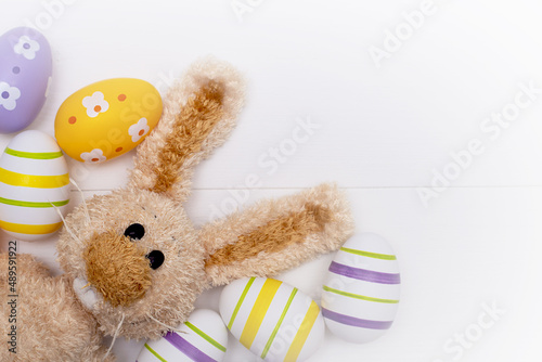 Easter composition - rabbit and multicolored eggs on a white wooden background. © Олеся Голубенко