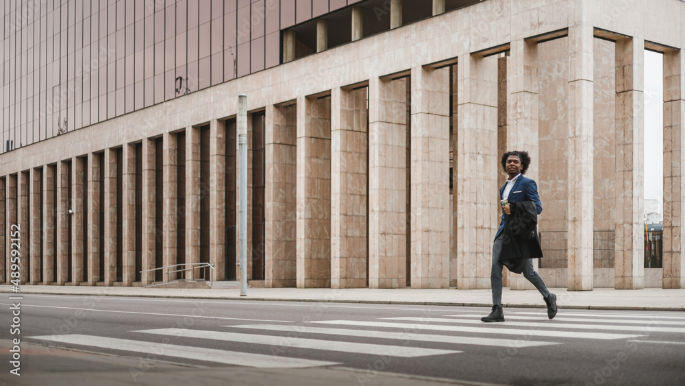 Big long shot of young african businessman crossing the street with happiness, space for copy Big long shot of young african businessman crossing the street with happiness, space for copy