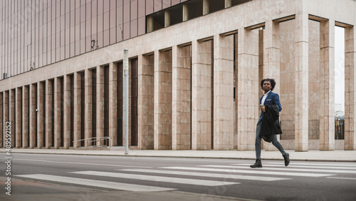 Big long shot of young african businessman crossing the street with happiness, space for copy