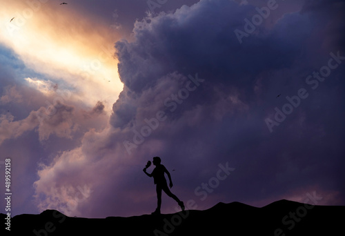 Silhouette of a person stands on the on the hill on  the sunset background.