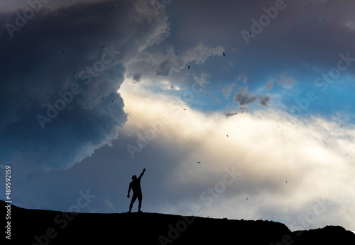 Silhouette of a person stands on the on the hill on the sunset background.
