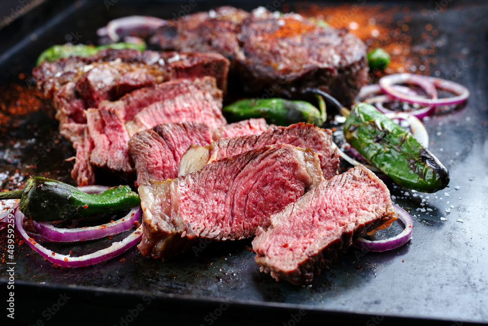 Traditional barbecue dry aged wagyu rib-eye beef steaks served with paprika and onion rings as close-up on an old rustic metal tray