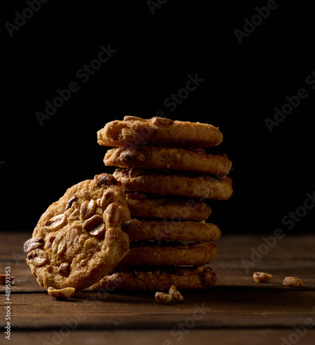 stack of baked round cookies on a wooden table, black background